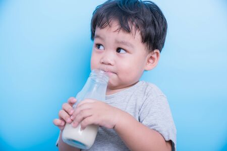Asian little baby boy drinking milk from bottle glassの写真素材