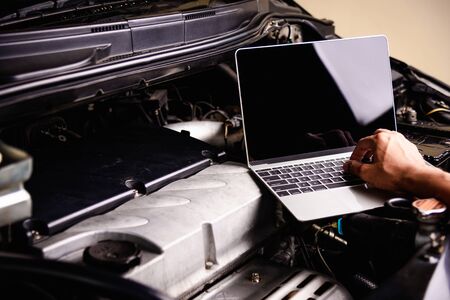 Professional car repair or maintenance mechanic engine working service with laptop computer at workshopの写真素材