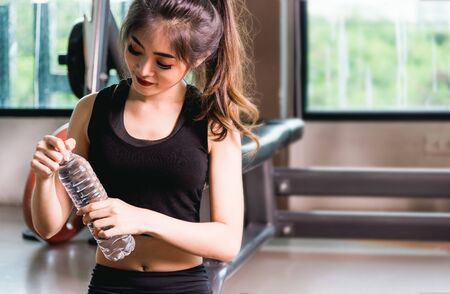 Woman drink water after exercise workout at fitness gymの写真素材