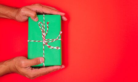 Happy New Year and Christmas 2020 or valentine day, top view hands with green gift box on red background with copy space for your textの写真素材