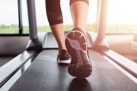 Feet of woman exercise workout running on treadmill at fitness gym