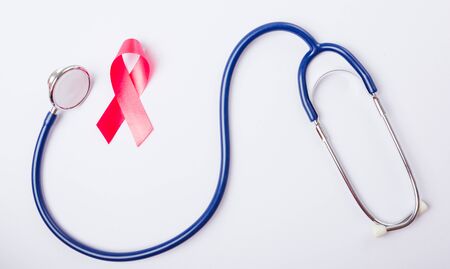 Breast cancer month concept, flat lay top view, pink ribbon and stethoscope on white background with copy space for your textの写真素材