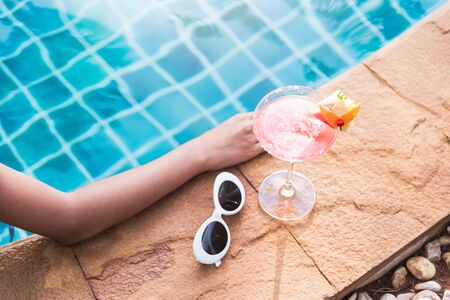 Young back woman in bikini luxury swimming pool drink cocktail, vacation summer holiday conceptの写真素材
