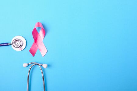 Breast cancer month concept, flat lay top view, pink ribbon and stethoscope on blue background with copy space for your textの写真素材