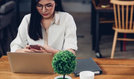 Freelance working woman with laptop computer, he using smartphone on job in coffee shop