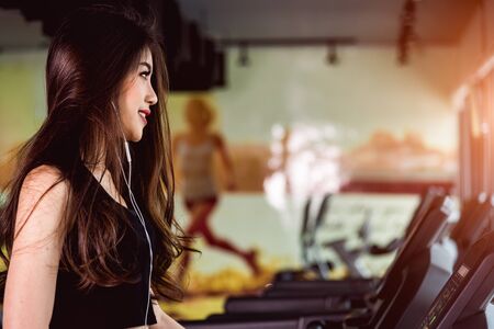 Woman lifestyle use technology smartphone music exercise on treadmill at fitness gymの写真素材