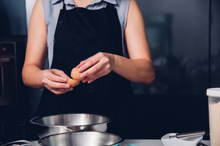 Woman girl baker in kitchen cooking whisk egg to bowl for bakery cakeの写真素材
