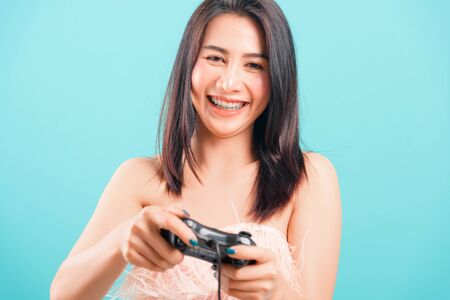 Smiling face portrait asian beautiful woman her playing video games by joy on blue background, with copy space for textの写真素材