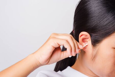 Asian beautiful woman cleaning ear hrt using cotton swab on white background with copy spece for text, healthcare conceptの写真素材