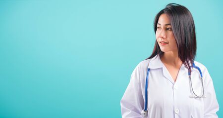 Portrait asian beautiful doctor woman smiling her standing with Hands in Pockets on blue background, with copy space for textの写真素材
