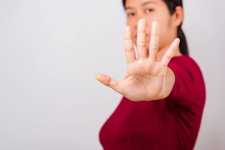 Asian beautiful woman itching her outstretched hand showing stop gesture front face, focus on hand on white background with copy spaceの写真素材