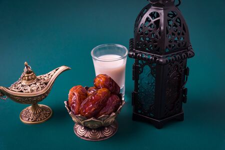Ramadan Kareem fasting Food Concept, Bronze plate dates, milk, and lantern Aladdin lamp decoration, eid Arabian Muslim religious festival on a dark green background with copy space for textの写真素材