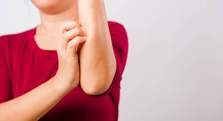 Asian beautiful woman itching her scratching her itchy arm on white background with copy space, Medical and Healthcare conceptの写真素材