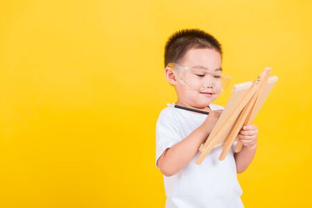 Asian Thai happy portrait cute little cheerful child boy smile are drawing on blackboard and looking...