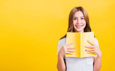 Portrait Asian Thai beautiful happy young lifestyle woman stands holding yellow book or diary her...