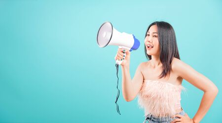 Smiling face portrait asian beautiful woman her usring megaphone on blue background, with copy space for textの写真素材
