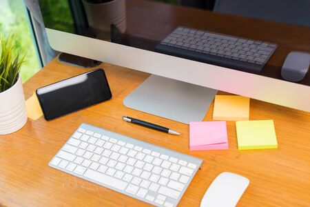 Home office interior blank screen desktop PC computer and smart phone decorations on desk under...