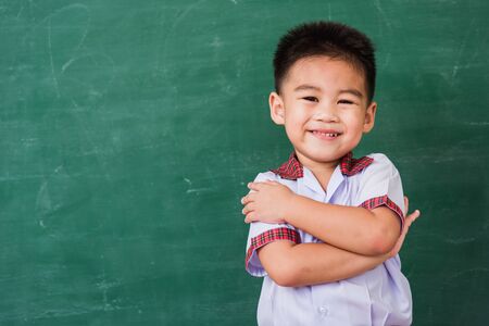 Back to School. Happy Asian funny cute little child boy from kindergarten in student uniform stand...