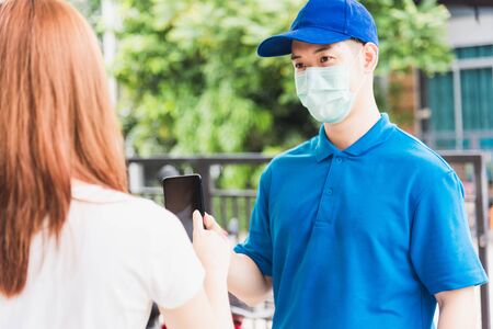 Asian delivery express courier young man giving parcel boxes to woman customer signature for...