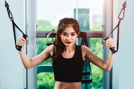 Beautiful woman exercise using machine crossover cable training workout at fitness gymの写真素材