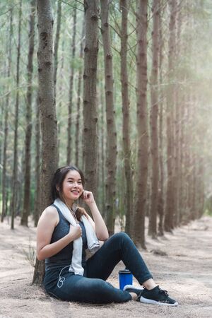 Beautiful sport young woman girl lifestyle exercise healthy break drinking water from bottle after running workout in forest nature park with copy spaceの写真素材