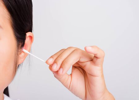 Asian beautiful woman cleaning ear hrt using cotton swab on white background with copy spece for text, healthcare conceptの写真素材