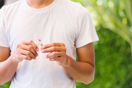 May 31 of World No Tobacco Day, Asian smoker man use hands breaking down cigarettes on green leaves...