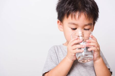Closeup Asian face, Little children boy drinking water from glass on white background with copy space, health medical careの写真素材