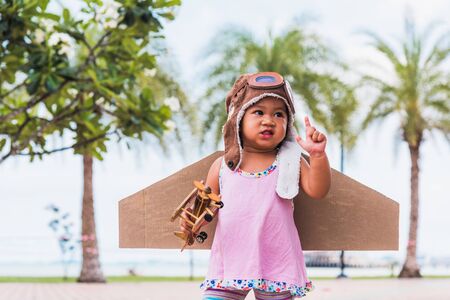Happy Asian funny child or kid little girl smile wear pilot hat and goggles play toy cardboard...