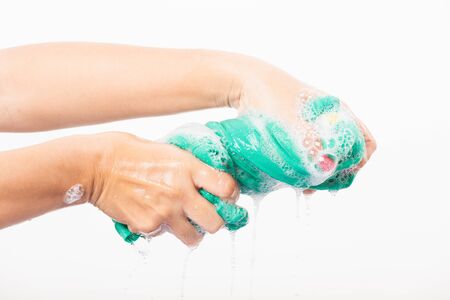 Closeup young Asian woman use hands wash color clothes. Female squeeze wring out wet fabric cloth with detergent have soapy bubble in water, studio shot isolated on white background, laundry conceptの写真素材