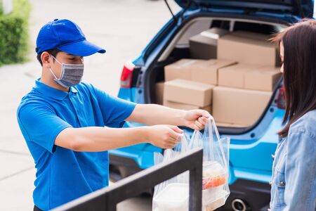 Asian young delivery man wear face mask he making grocery service giving rice food boxes plastic...