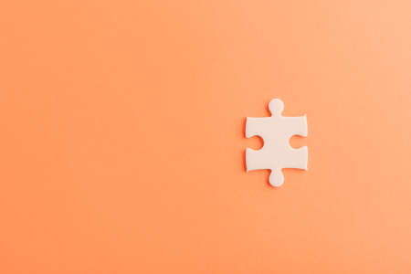 Top view flat lay of one paper plain white jigsaw puzzle game last pieces for solve, studio shot on an orange background, quiz calculation conceptの写真素材