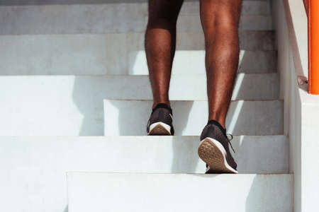 Close up athlete shoes of legs young sport runner black man step running up to climbing stairs doing training cardio sport workout at the outdoor street, healthy exercise before workout conceptの写真素材
