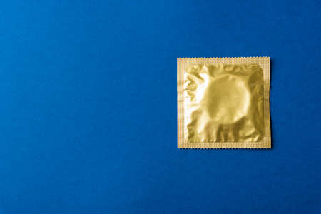 World sexual health or Aids day, Top view flat lay condom in wrapper pack, studio shot isolated on a dark blue background, Safe sex and reproductive health conceptの写真素材