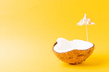Happy coconuts day concept, fresh coconut and sun umbrella, studio shot isolated on yellow...
