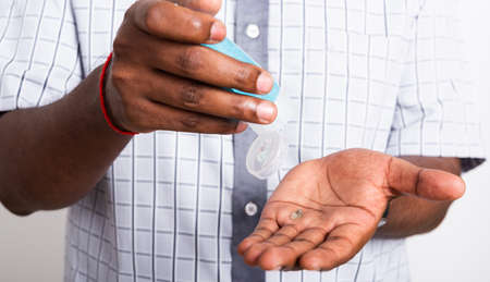 Closeup Asian black man wearing protective face mask  use sanitizer gel face clean his hand, hygiene prevention COVID-19 virus or coronavirus protection concept isolated on white backgroundの写真素材