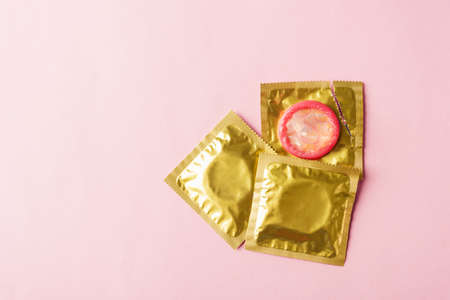 World sexual health or Aids day, Top view flat lay condom in wrapper pack is tear open, studio shot isolated on a pink background, Safe sex and reproductive health conceptの写真素材