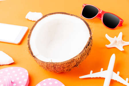 Happy coconuts day concept, fresh coconut, and summer accessories (model plane, sunglasses, smartphone, starfish and slippers), Beach tropical fruit trip journey and spring-summer holidayの写真素材