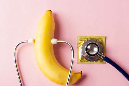 World sexual health or Aids day, Top view flat lay condom in wrapper pack, banana and doctor...