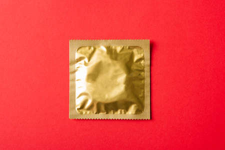 World sexual health or Aids day, Top view flat lay condom in wrapper pack, studio shot isolated on a red background, Safe sex and reproductive health conceptの写真素材
