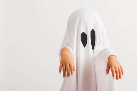 Funny Halloween Kid Concept, little cute child with white dressed costume halloween ghost scary, studio shot isolated on white backgroundの写真素材