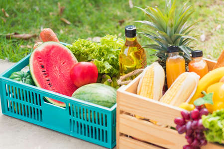 Full fresh vegetables and fruits in crate wood box, harvest organic food on the garden place of green leaves color background for copy space, Eat healthy conceptの写真素材