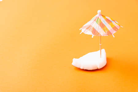 Happy coconuts day concept, fresh coconut pieces slices and sun umbrella, studio shot isolated on orange background, Beach tropical fruit spring summer holidayの写真素材