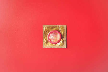 World sexual health or Aids day, Top view flat lay condom in wrapper pack is tear open, studio shot isolated on a red background, Safe sex and reproductive health conceptの写真素材