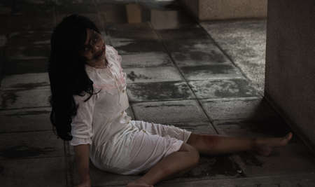 Girl zombie in blood. Asian Woman ghost with blood. Horror creepy scary fear she sitting in a dark house. Hair covering the face, Halloween festival conceptの写真素材