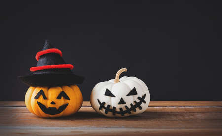 Funny Halloween day party concept ghost pumpkins head jack lantern scary smile wear hat on wooden table and black background, studio shot isolated, Holiday decorationの写真素材