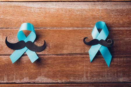 November Blue, Light blue ribbon with a man mustache on wooden background,  Men health awareness, Prostate Cancer Awarenessの写真素材