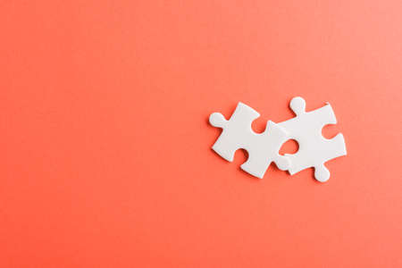 Top view flat lay of two paper plain white jigsaw puzzle game last pieces for solve, studio shot on a red background, quiz calculation conceptの写真素材