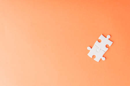 Top view flat lay of two paper plain white jigsaw puzzle game last pieces for solve, studio shot on an orange background, quiz calculation conceptの写真素材