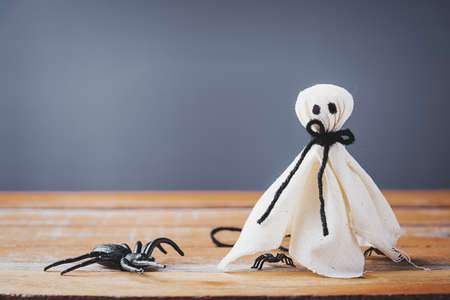 Funny Halloween day decoration party, closeup white ghost and spider on wooden wall gray background and copy space, studio shot isolated, Happy holiday conceptの写真素材